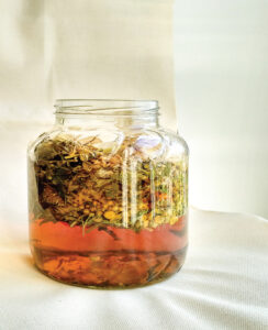 glass jar filled with pink liquid and herbs